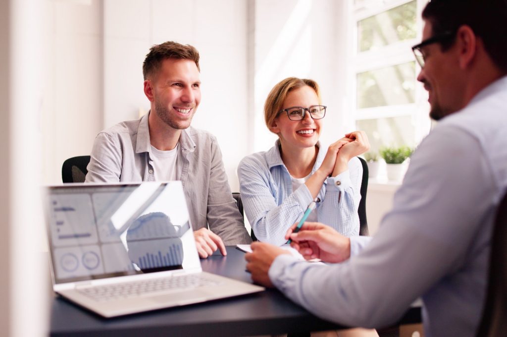 A couple happily talking with their financial planner.